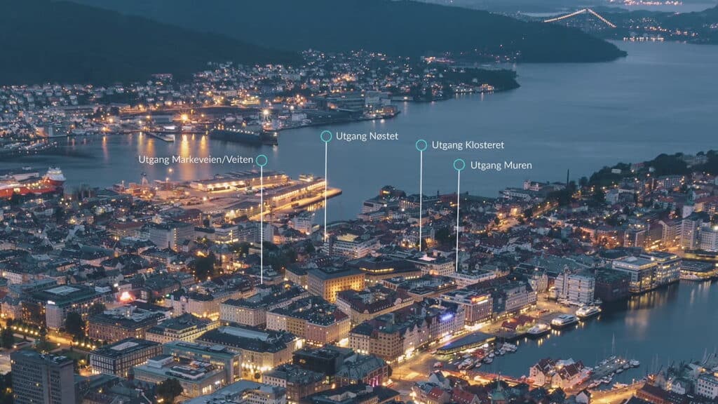 Flyfoto av en Bergen sentrum i skumringen med markerte steder: Markveien/Veiten, Nøstet, Klosteret og Muren som viser tilgang til KlosterGarasjen. Bygninger, vannveier, broer og parkering i Bergen sentrum er synlige.