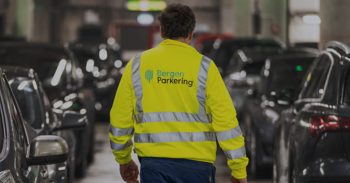 Bilde av en mann sett bakfra som går i GriegGarasjen. Han har på seg synlighetstøy med logoen til Bergen Parkering på ryggen.