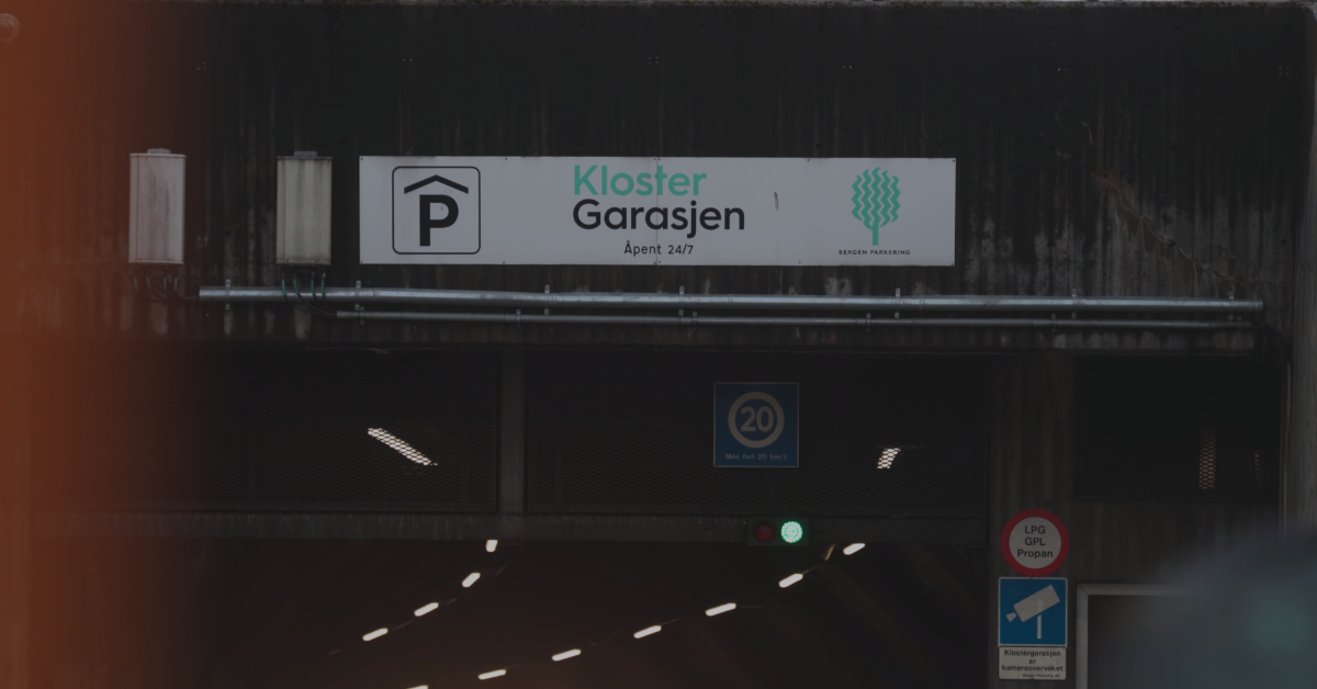 Bilde av portalskiltet over innkjøringen til KlosterGarasjen, med fokus på navn og logo.