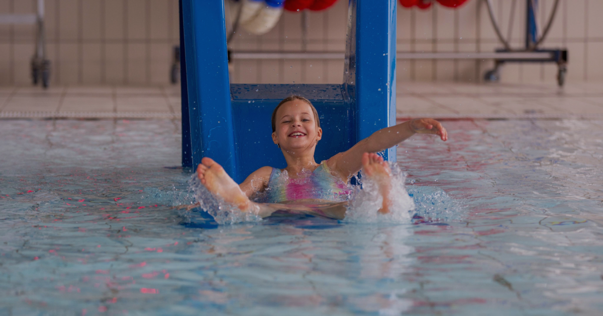Bilde av et jentebarn som kommer ned vannsklie og plasker ned i et basseng
