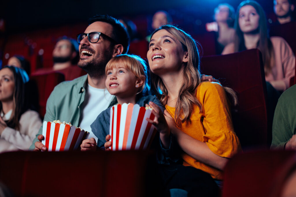 Bilde av en familie som sitter i kinoseter og ser opp mot et lerret.